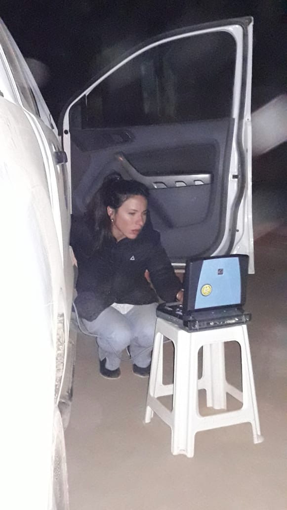 Ultrasound technician performing ultrasound using mobile unit; patient seated in pick-up truck’s front seat, La Abispa community in Salta, Argentina. Photograph by Santiago L. Cunial, August 2019.